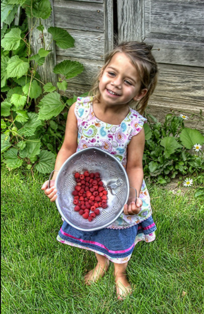 Girl holding a bowl of Raspberries
